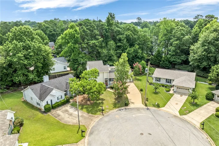 An aerial perspective reveals three homes nestled amidst verdant trees within a tranquil cul-de-sac.