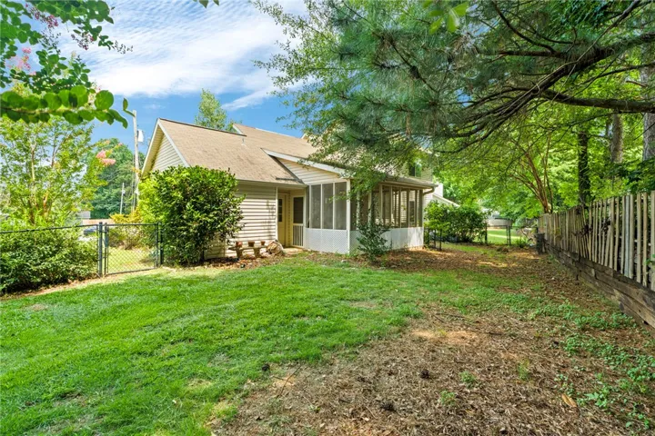 A private, fenced backyard offers a serene escape with mature trees providing ample shade.