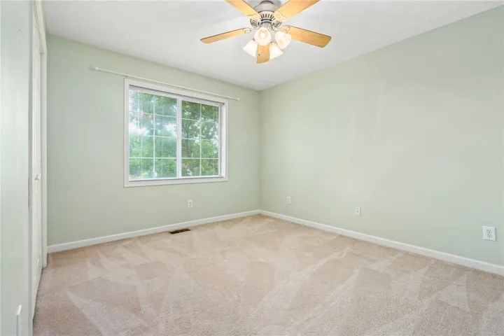 A quiet bedroom offers ample space, a large window, and a ceiling fan for comfort.