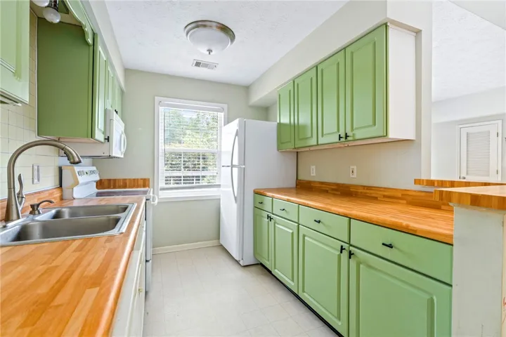 Butcher block countertops complement vibrant green cabinetry in this efficient kitchen space.