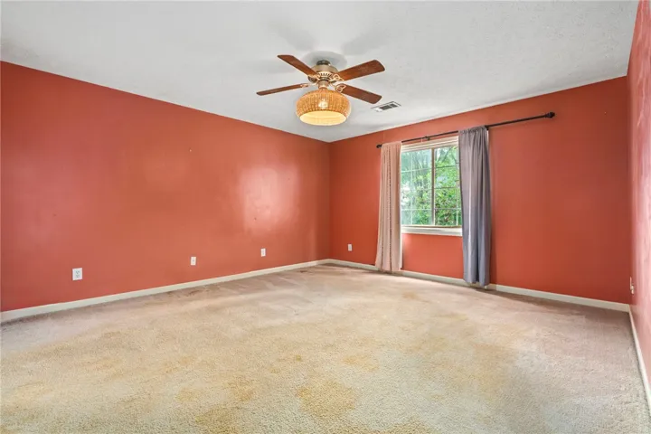 A well-lit room featuring ample natural light from a large window and a modern ceiling fan.