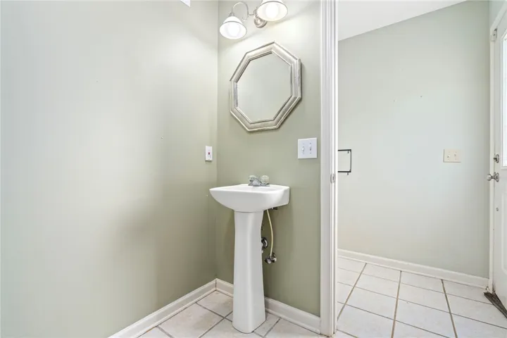 A compact half bath with a classic pedestal sink and ample vanity lighting.
