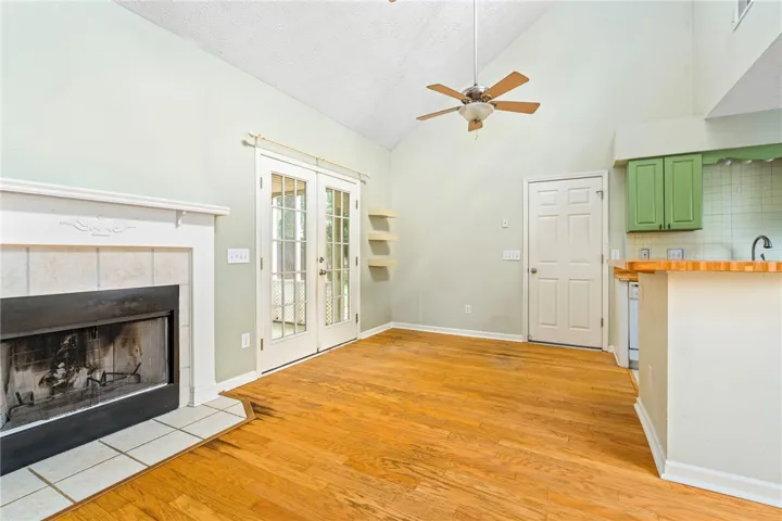 A cozy living space features a tiled fireplace, rich hardwood flooring, and soaring vaulted ceilings.