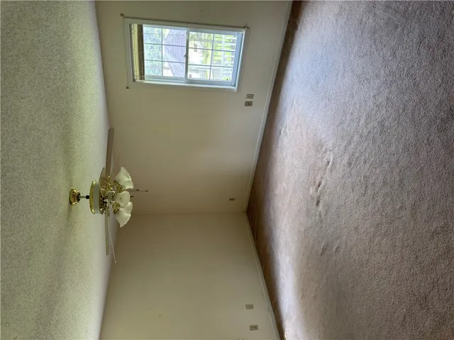 A well-lit bedroom features plush carpeting and a convenient window for natural light.