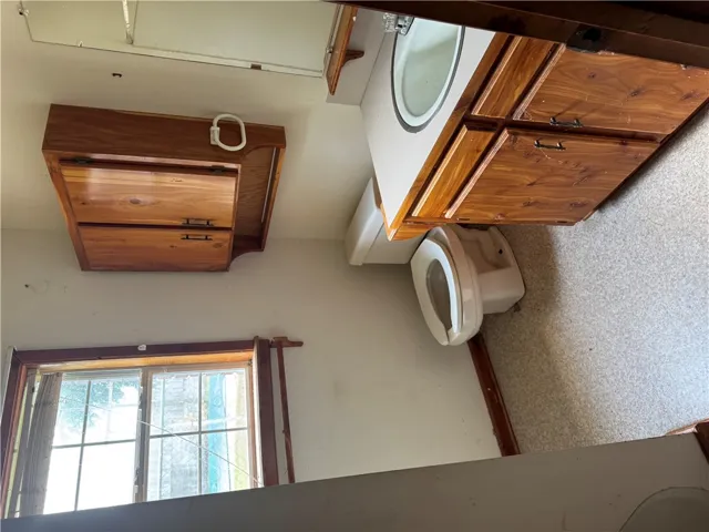 A window-filled bathroom featuring wood cabinetry and an integrated sink.