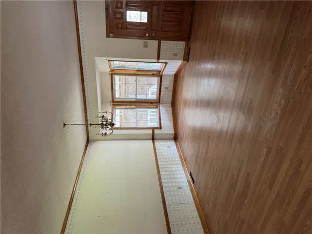 A classic chandelier illuminates a room featuring bay windows and wood flooring, ready for personalization.