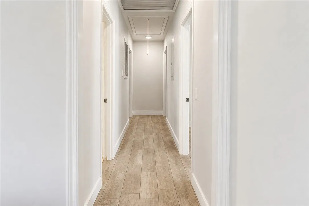 Corridor with neutral tones and wood-look flooring connects various rooms within the residence.