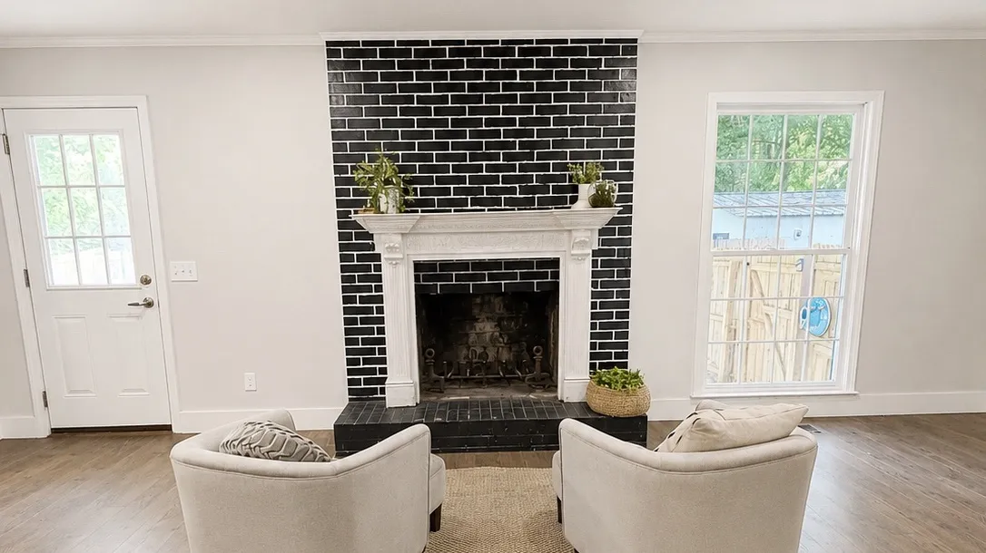 Fireplace, with a black brick facade and white mantel, creates a bold focal point.