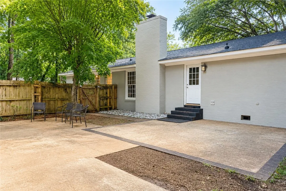 A spacious backyard patio provides ample space for relaxation and entertaining, bordered by a privacy fence and lush trees.