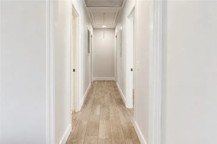 Corridor with neutral tones and wood-look flooring connects various rooms within the residence.