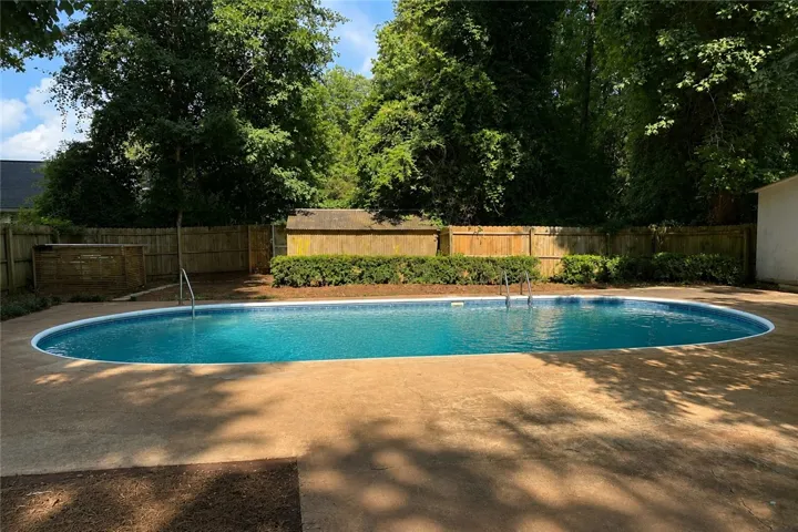 An inviting oval pool anchors the spacious backyard, offering a refreshing retreat amidst established landscaping.