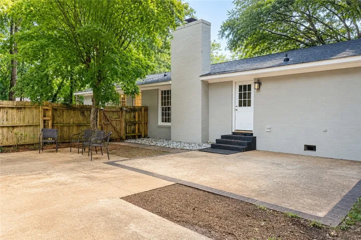 A spacious backyard patio provides ample space for relaxation and entertaining, bordered by a privacy fence and lush trees.