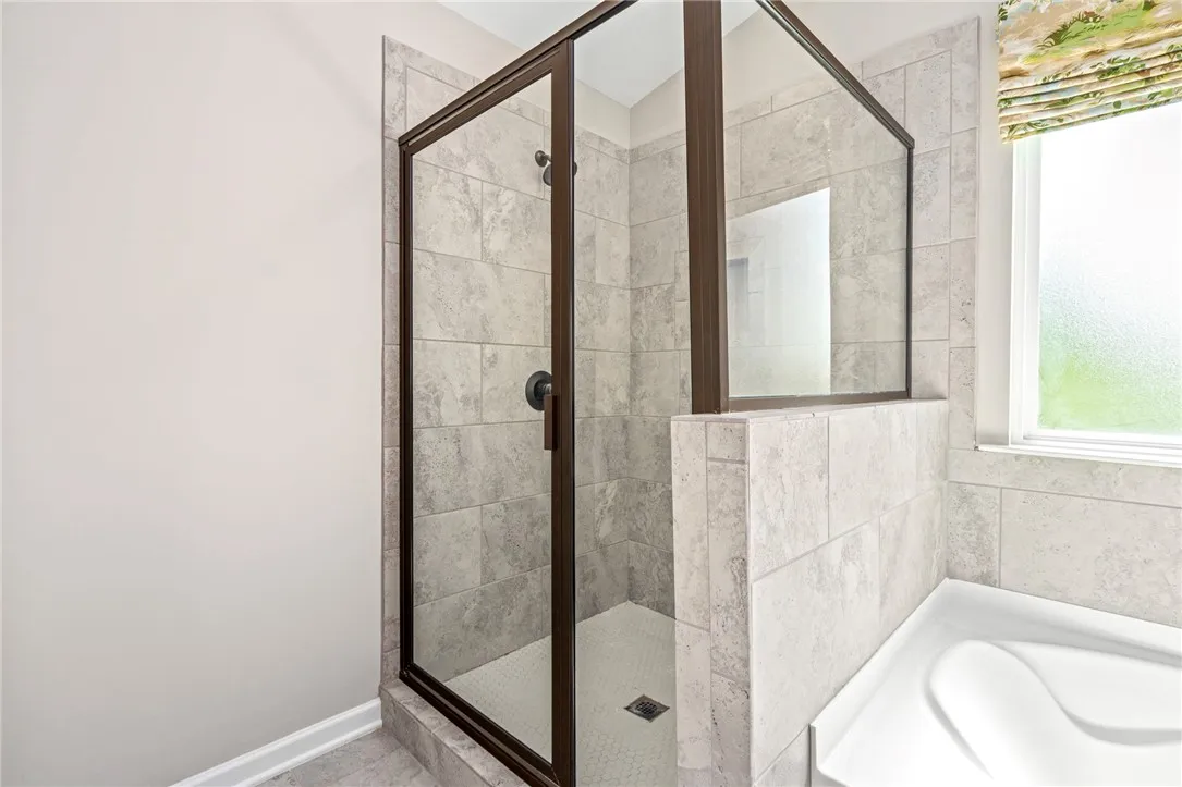 A well-appointed shower enclosure with tile flooring and glass doors creates a refreshing bathroom retreat.