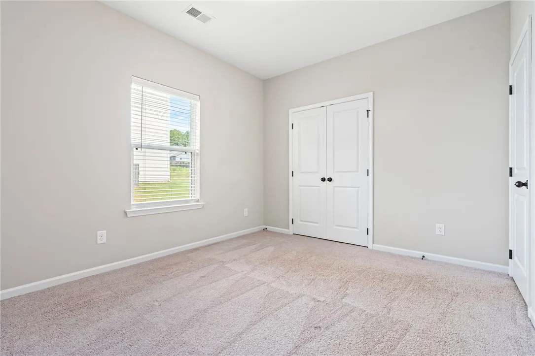 Downstairs Bedroom. An airy bedroom with plush carpeting and a large window offers a serene retreat.
