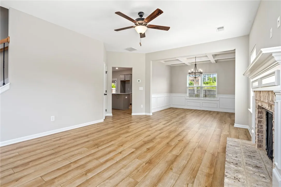 An open floorplan living area features durable hardwood flooring and a classic fireplace, perfect for gathering.