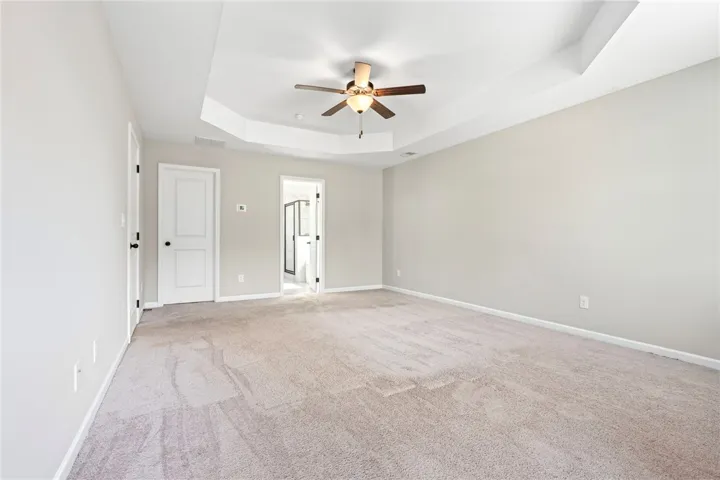 An inviting sleeping quarters, complete with tray ceiling and plush carpeting, offers a peaceful retreat.