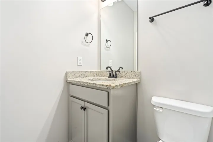 Downstairs Bathroom. A corner vanity with stone counters and a sleek black faucet anchors this pristine powder room.