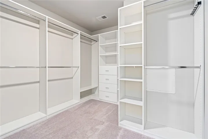 Ample storage solutions await in this naturally illuminated walk-in closet with built-in shelving and soft carpeting.