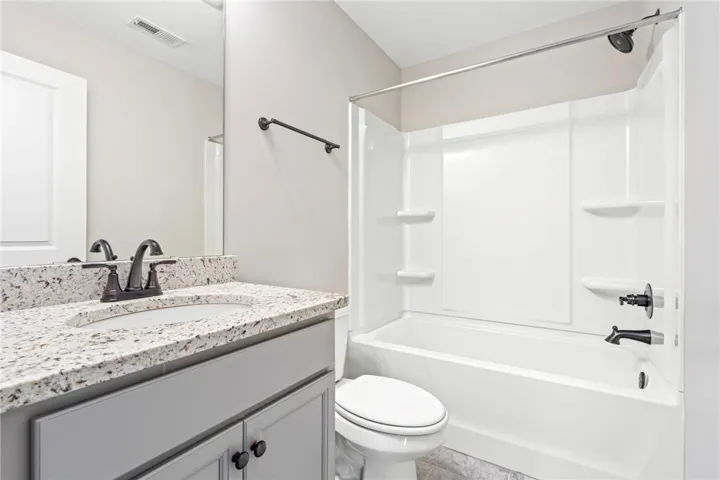 Modern bath offering a tub/shower combination, complemented by a spacious vanity with granite counters.