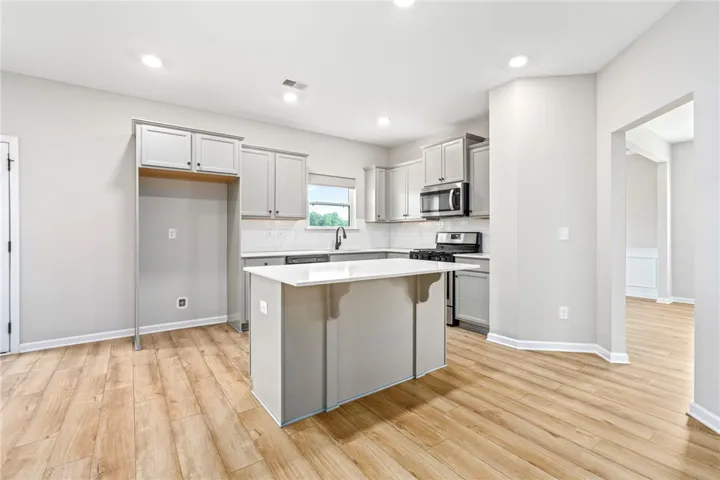 A pristine kitchen features an island, ample cabinetry, and sleek appliances.