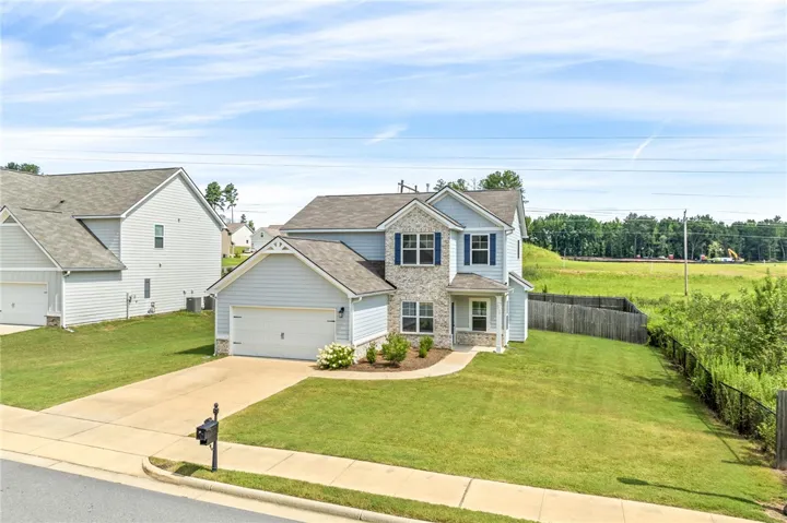 A classic two-story residence with a stone and siding facade offers a generous private yard.