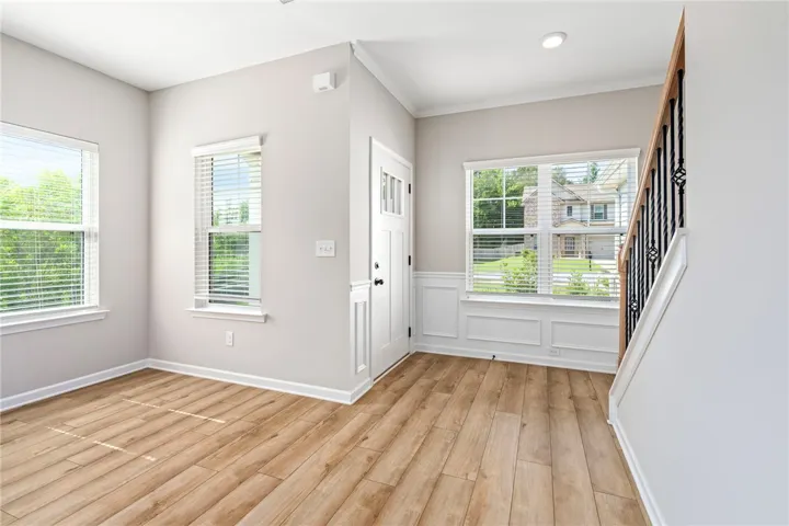 A well-lit entry with rich hardwood flooring and a stylish wrought iron staircase.