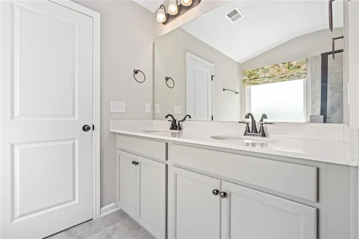 Double vanity with ample counter space and well-lit mirror offers a bright start to each day.