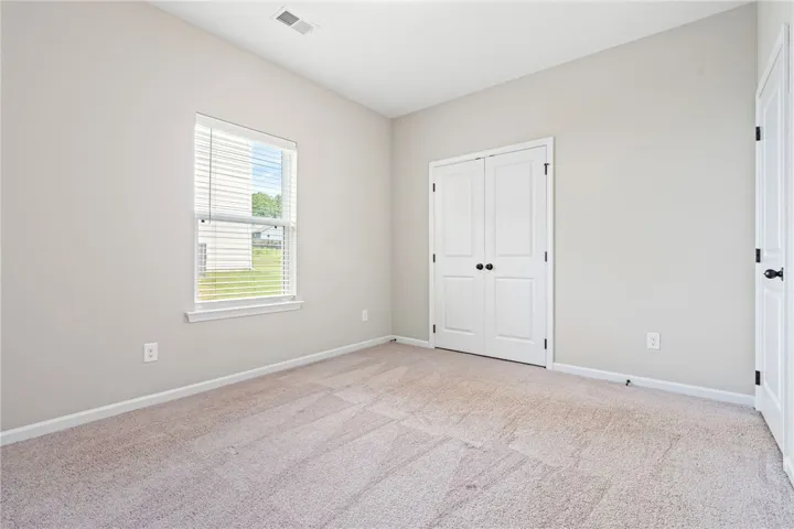 Downstairs Bedroom. An airy bedroom with plush carpeting and a large window offers a serene retreat.