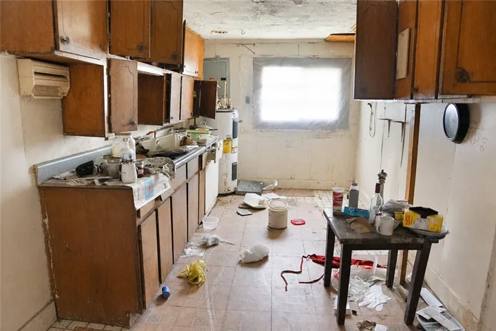 A utilitarian kitchen awaiting transformation, featuring modest cabinetry and a water heater.