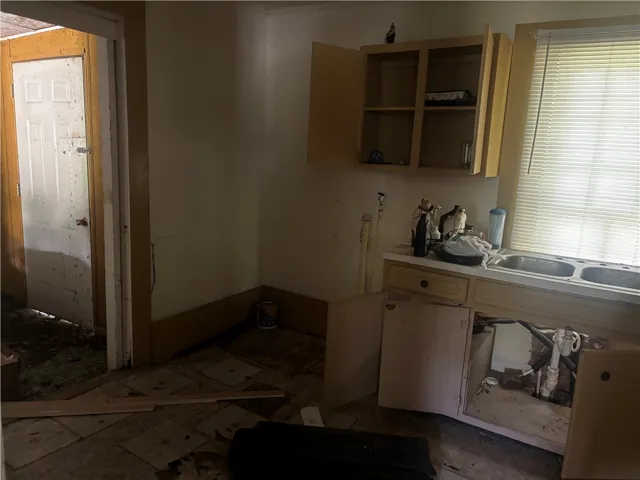 A well-lit window overlooks a functional kitchen featuring ample cabinet space and dual basin sink.