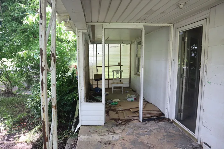 A partially enclosed patio space with concrete flooring offers a sheltered transition to the outdoors.