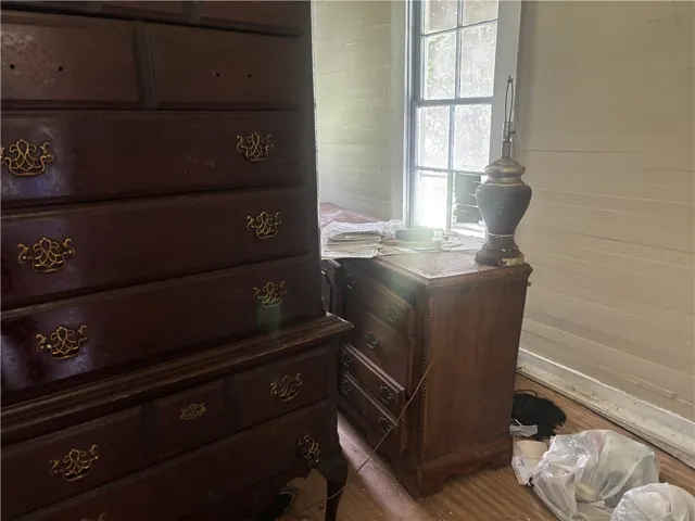 A well-lit bedroom space with charming wood floors and a functional window overlooking the surroundings.