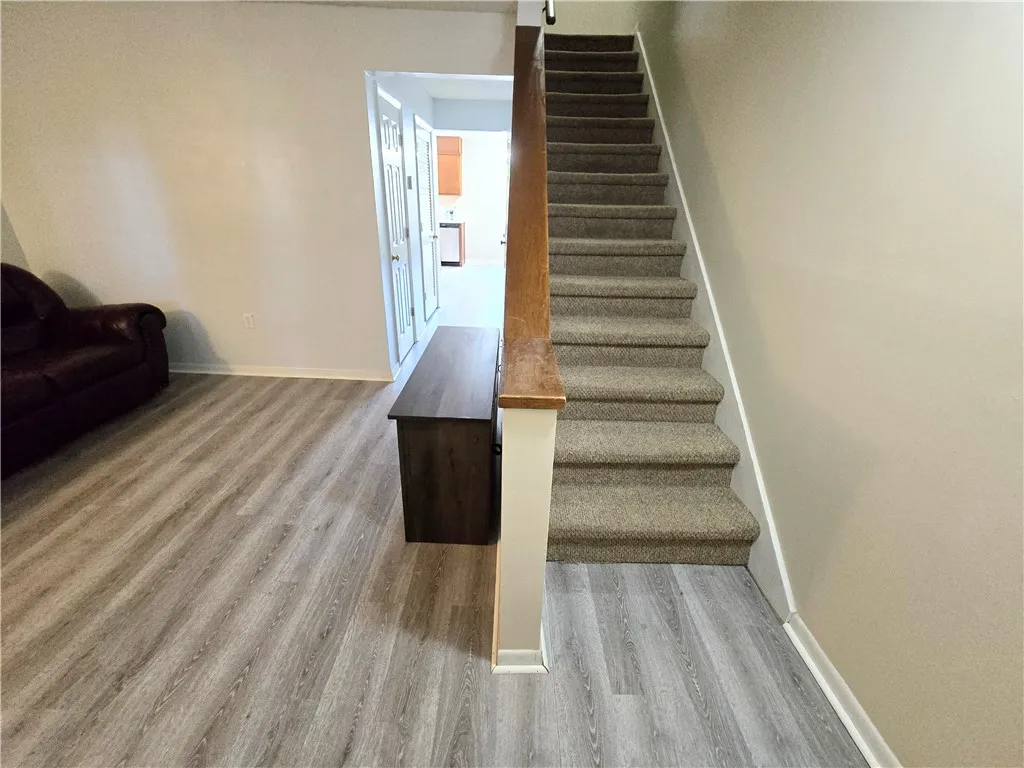A striking stairway with plush carpeting ascends from stylish wood plank flooring.