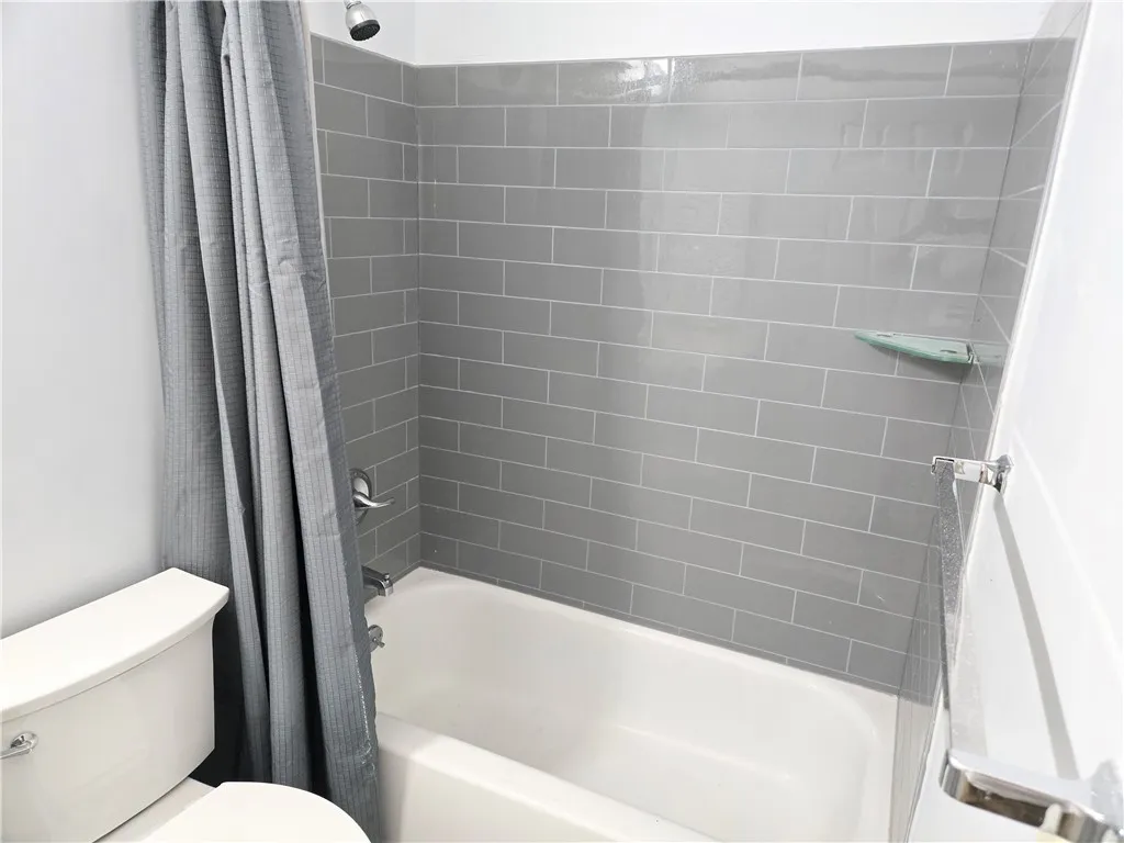 A pristine tub and shower combination with sleek gray tile work offers a refreshing retreat.