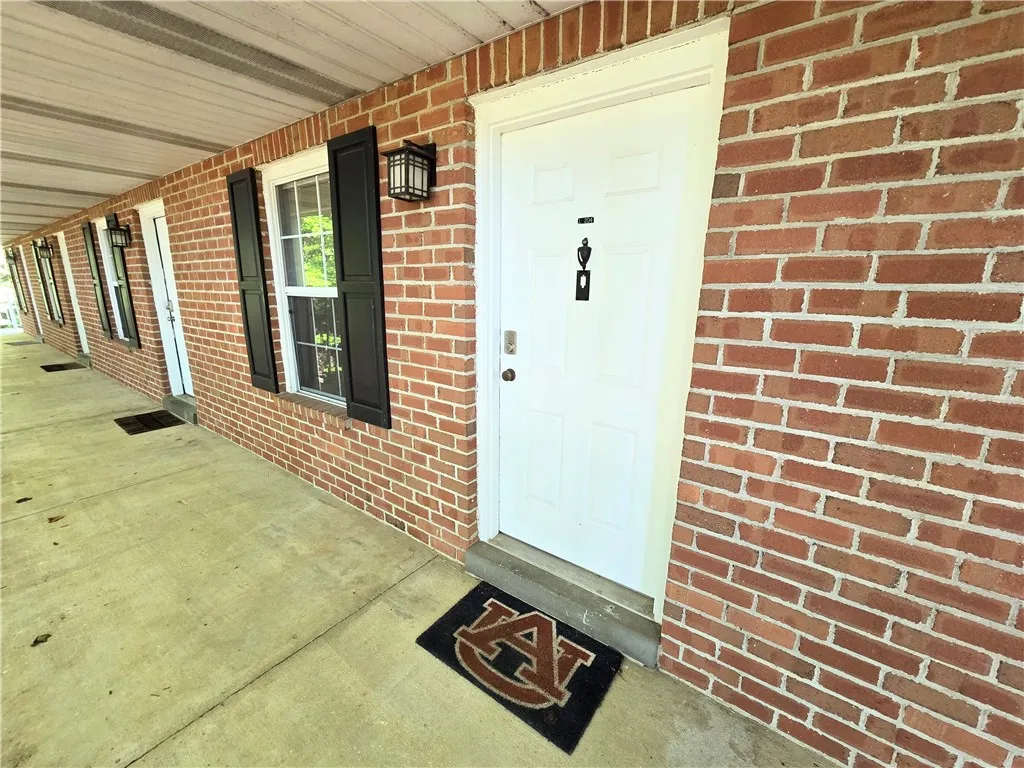 A classic brick exterior offers individual entries for each residence along a covered walkway.