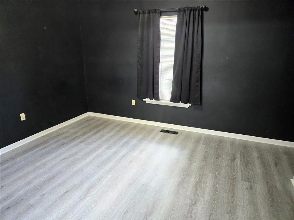 Laminate flooring and a window with blinds define this versatile room.