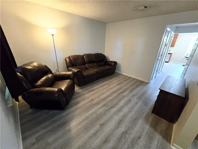 The living area features durable vinyl plank flooring, extending into an adjacent kitchen space.