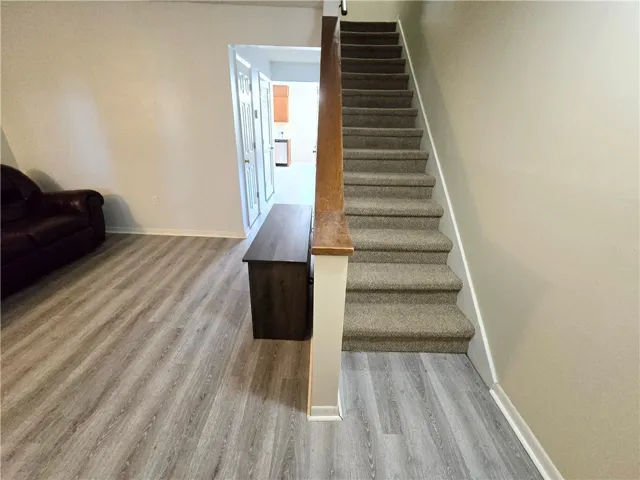 A striking stairway with plush carpeting ascends from stylish wood plank flooring.