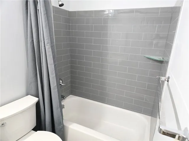 A pristine tub and shower combination with sleek gray tile work offers a refreshing retreat.