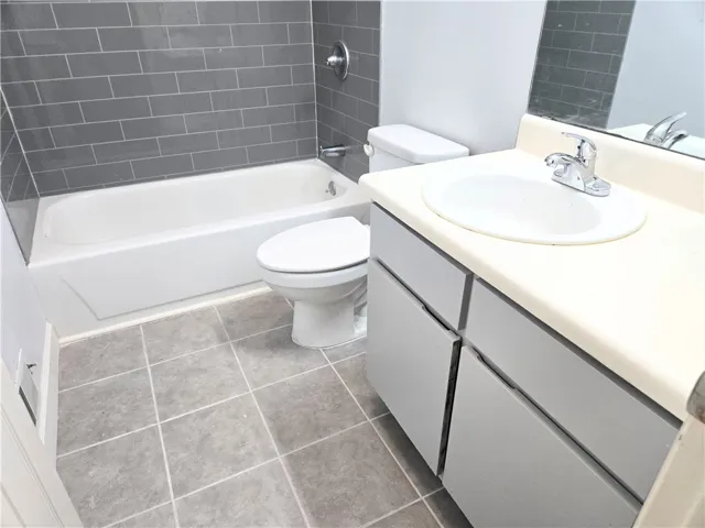 Refreshed bathroom featuring modern tile work around the tub and a convenient vanity.