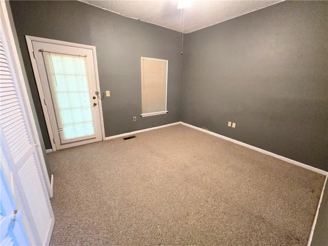 A well-lit bedroom offering direct outdoor access and comfortable carpeting.