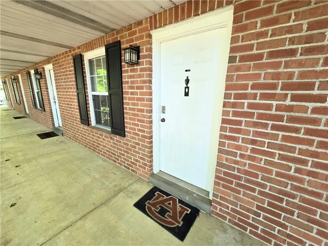 A classic brick exterior offers individual entries for each residence along a covered walkway.