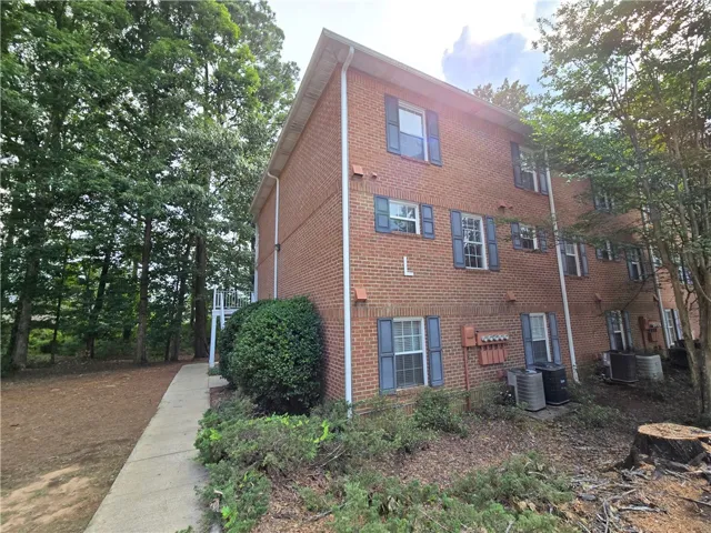 Mature trees and neat landscaping frame this brick apartment complex with a private side walkway.