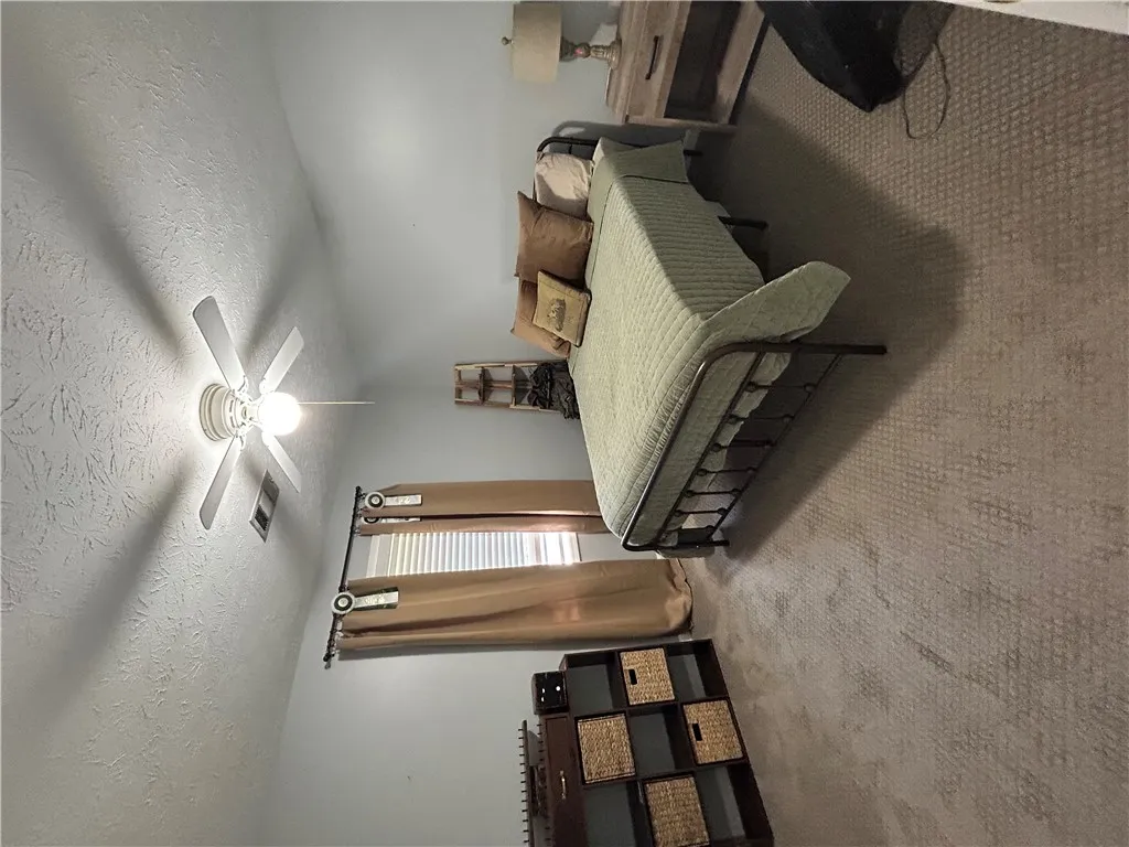 Relax in this comfortable bedroom featuring soft carpeting and natural light.
