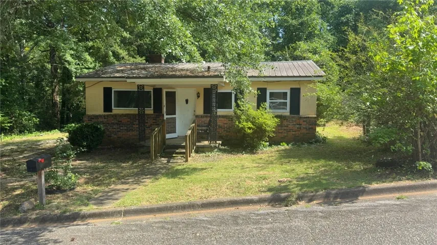 A charming single-story residence with a welcoming front porch and mature trees for natural shade.