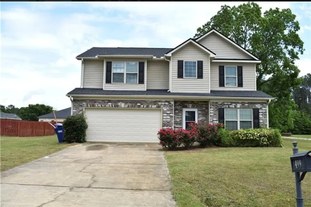 A classic two-story home with a neat driveway and inviting shrubbery.