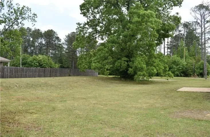 A spacious, verdant lot bordered by a classic wooden privacy fence, perfect for outdoor living.