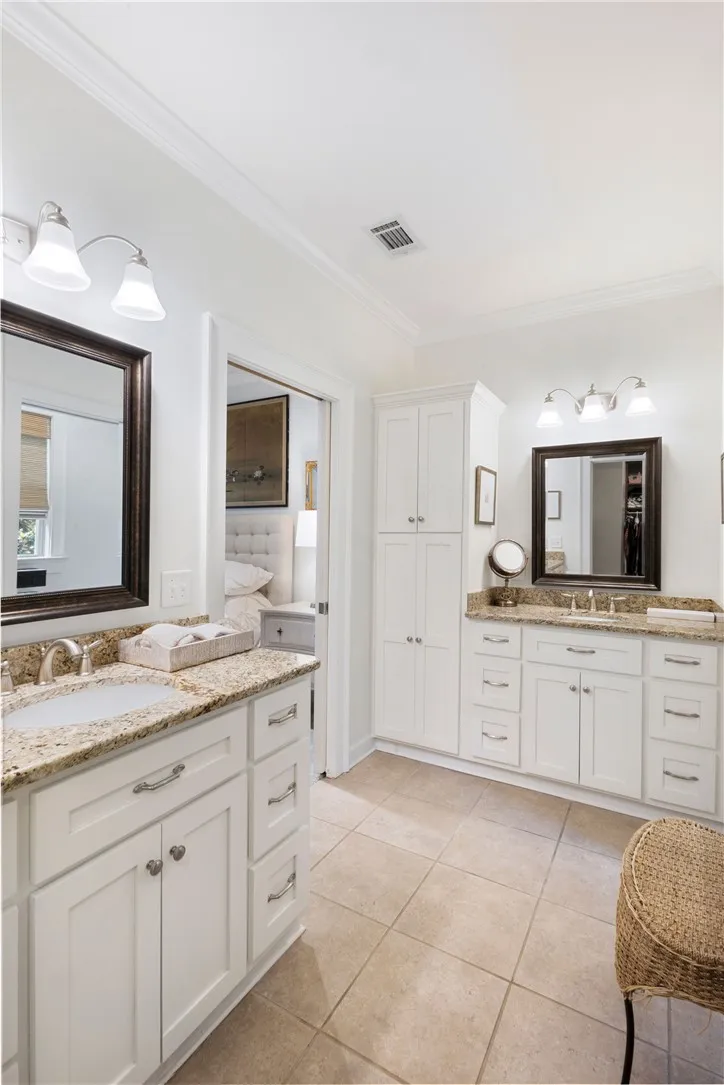 Dual vanities with granite counters and bright white cabinetry provide ample space in this well-appointed bath.