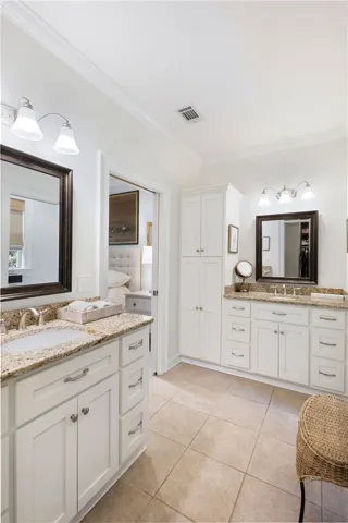 Dual vanities with granite counters and bright white cabinetry provide ample space in this well-appointed bath.