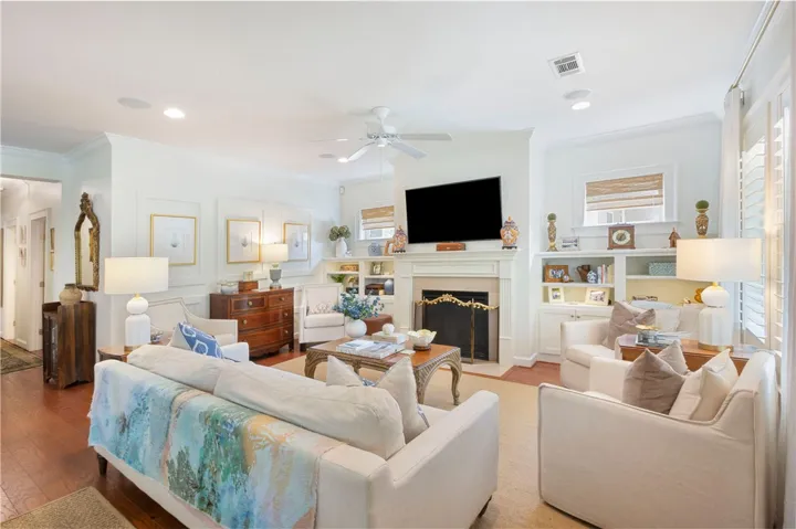 Hardwood floors and built-in shelving complement this inviting, well-lit living area centered by a fireplace.